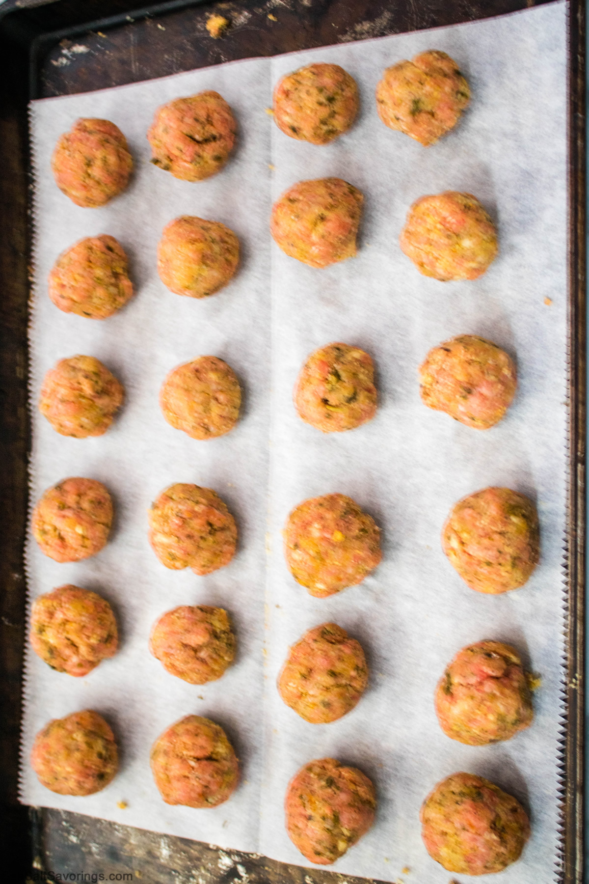 sheet pan of small meatballs placed in rows ready to bake