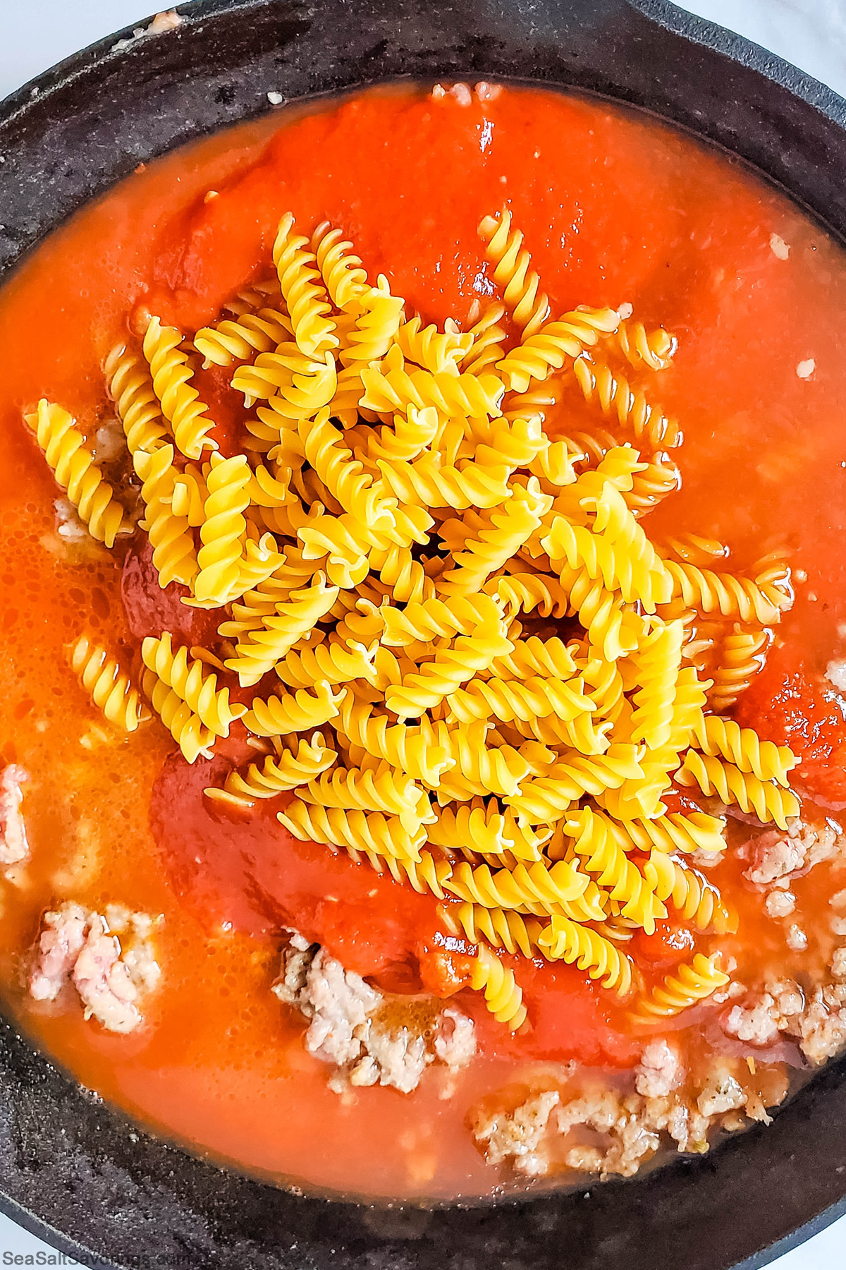 step photo of adding dry noodles to the mixture for the lasagna