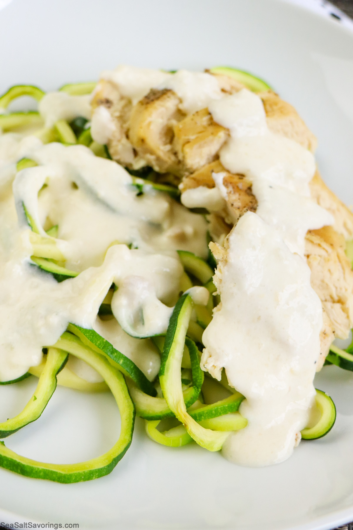 close up view of creamy alfredo on a bed of zoodles