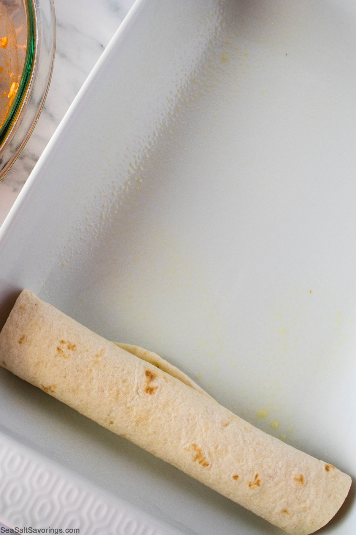 rolled up tortilla added to a baking dish