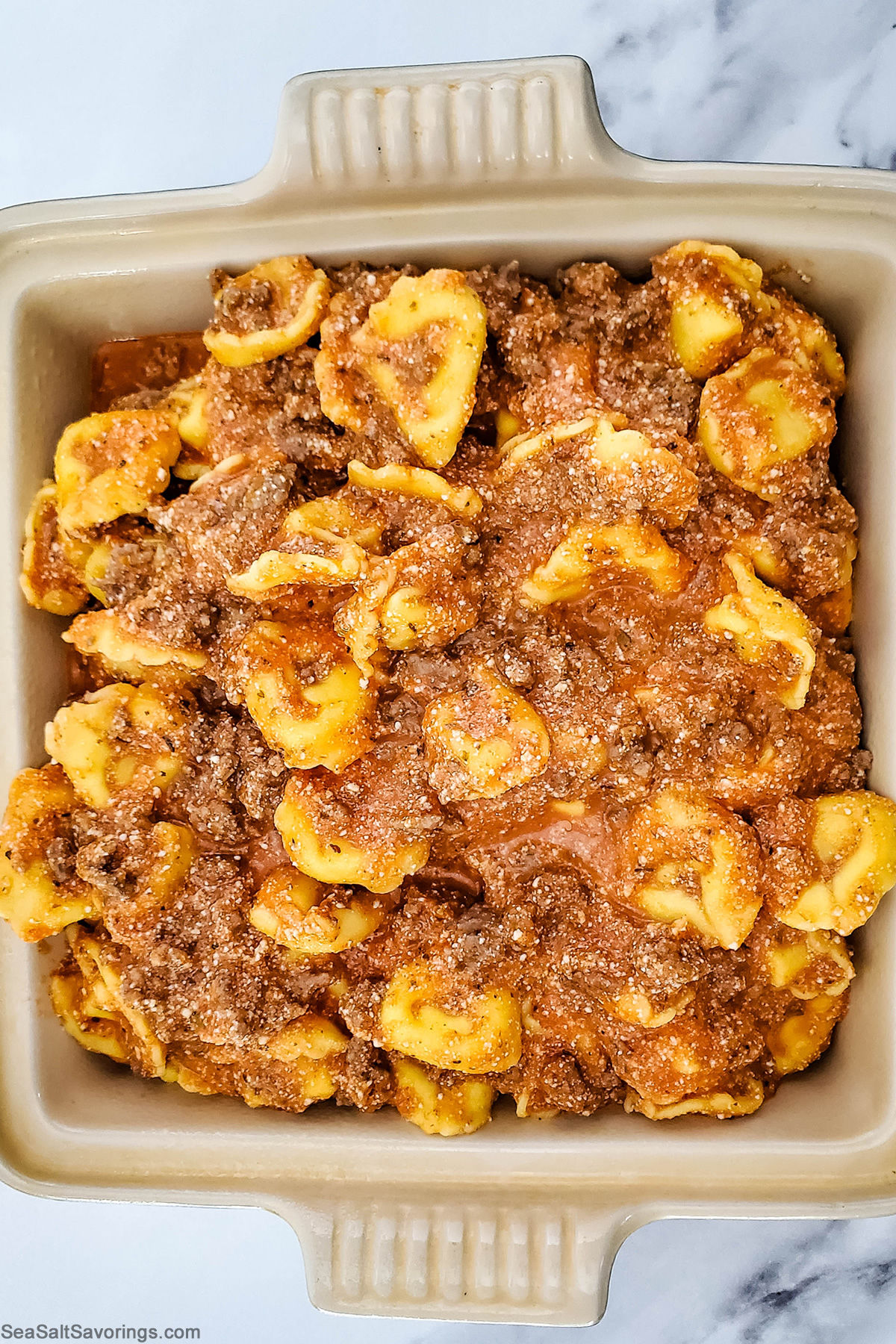 adding tortellini filling to baking dish