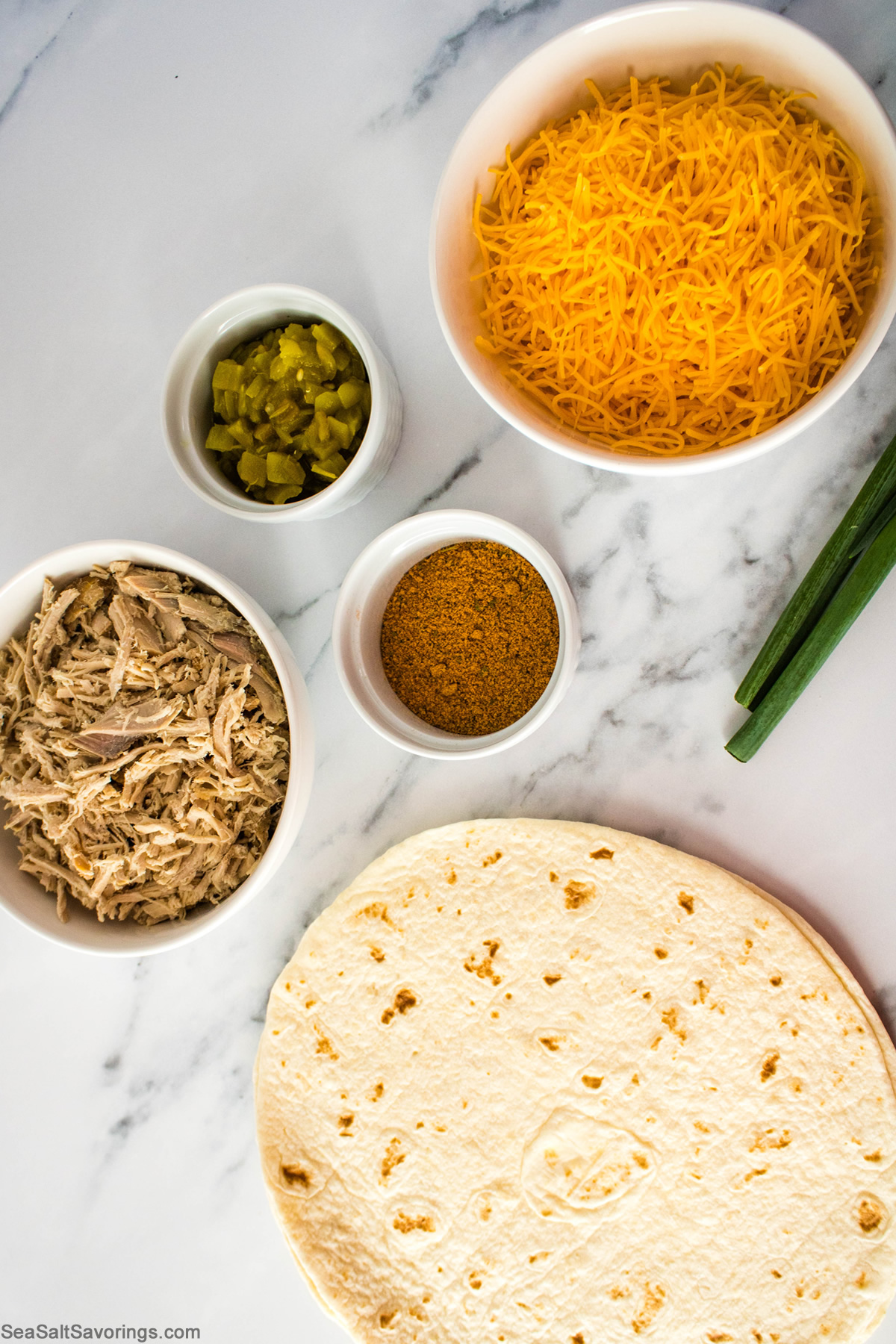 simple ingredients for shredded pork quesadillas including cheese and spices and pork