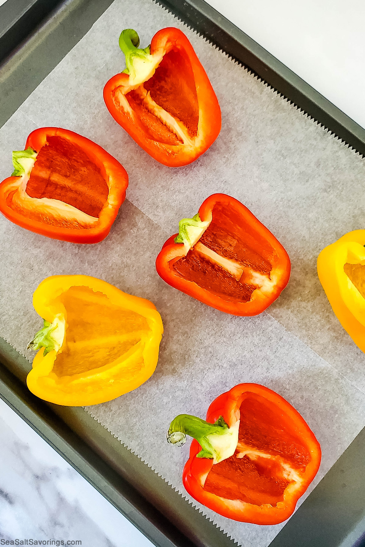 bell peppers sliced in half and laid on a baking pan