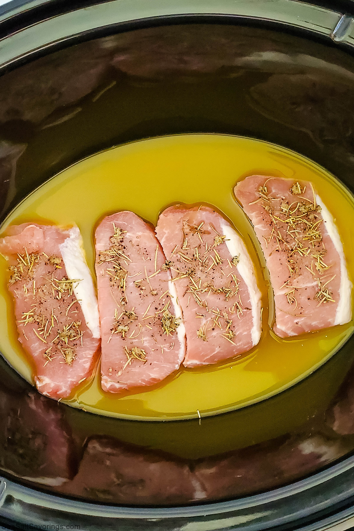 pork chops placed in a crock pot and sprinkled with season