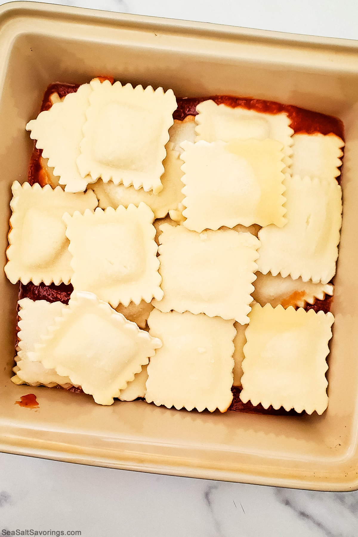 layering raviolis in a air fryer basket