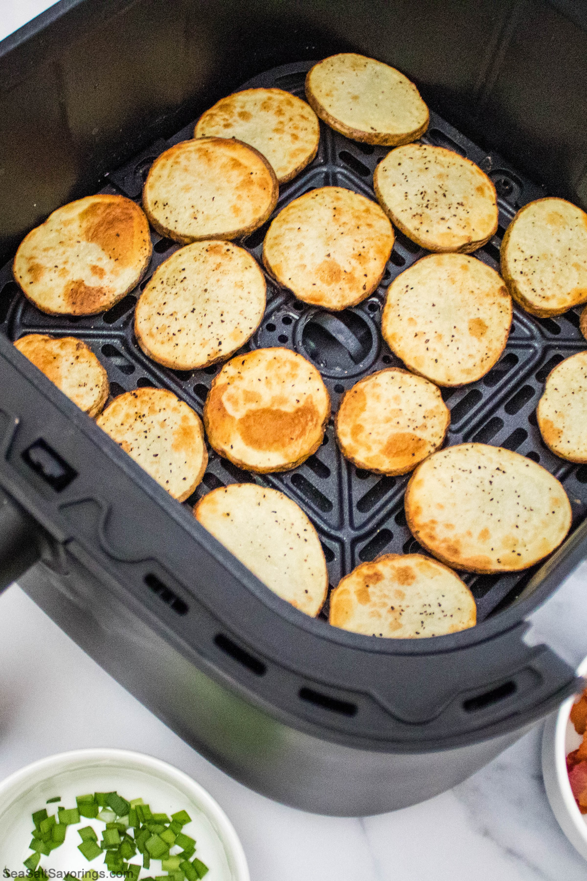 potato slices seasoned and placed in air fryer basket