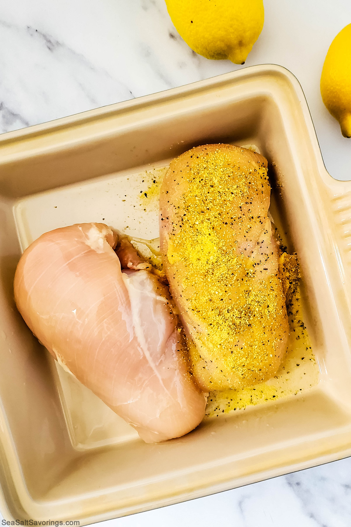 overhead view of air fryer basket with chicken breasts in it