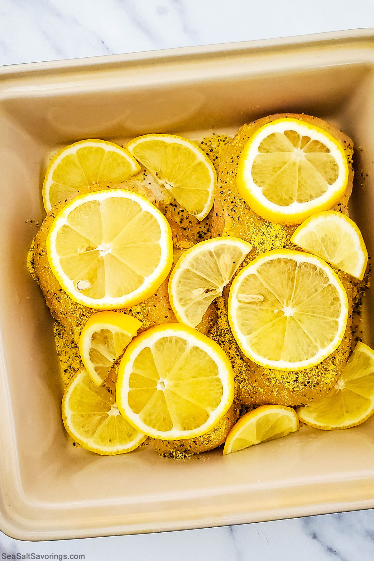 air fryer basket filled with chicken breasts and topped with lemon