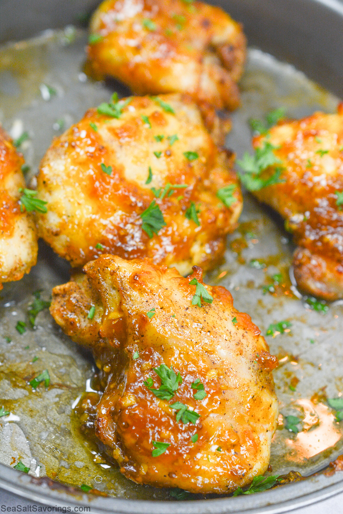 glazed chicken thighs cooking in pan