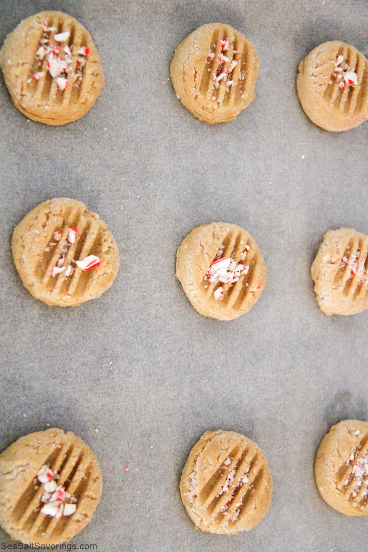 cookie dough formed and shaped and placed on a cookie sheet and topped with crushed candy cane