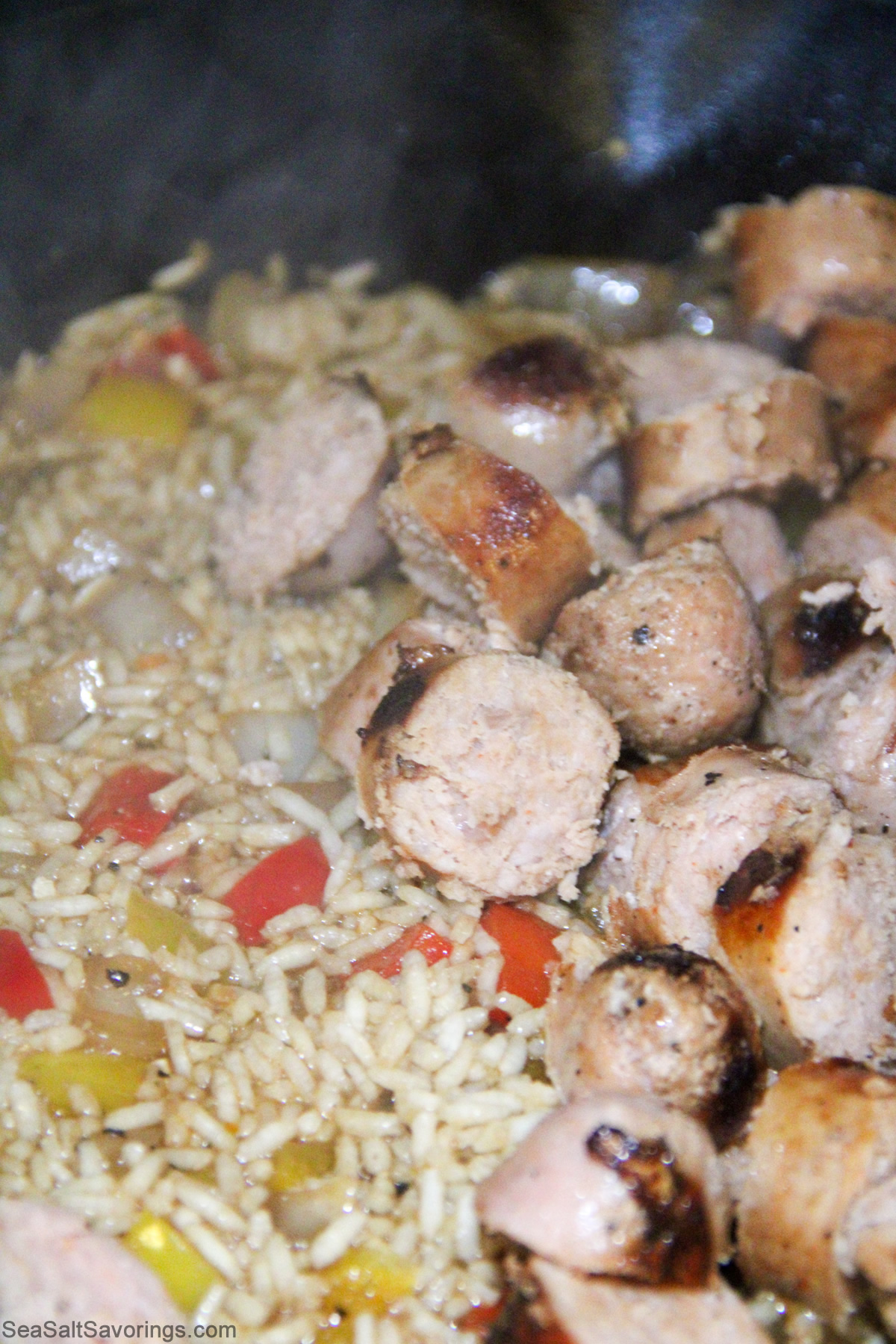 chopped sausages mixed in frying pan with vegetables to cook