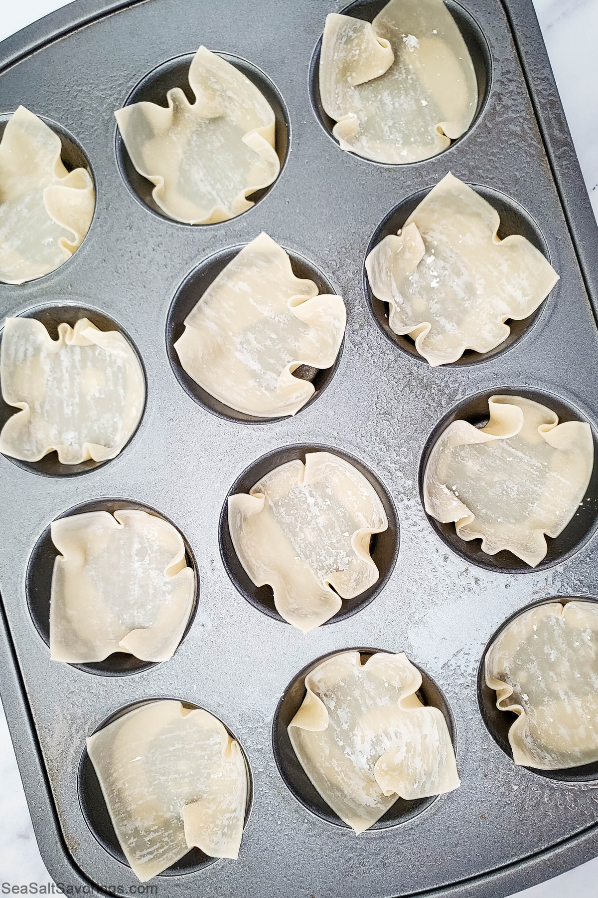 empty wonton cup shells lined in a cupcake cooking sheet