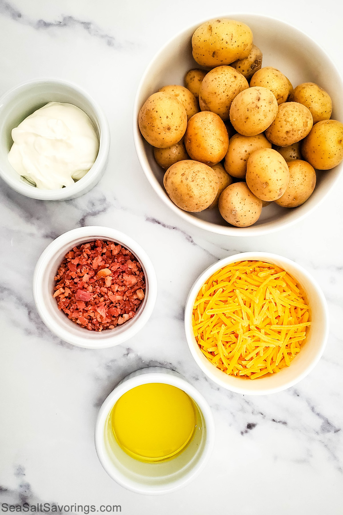 ingredients for mini baked potatoes such as potatoes and bowls of sour cream, bacon and cheese