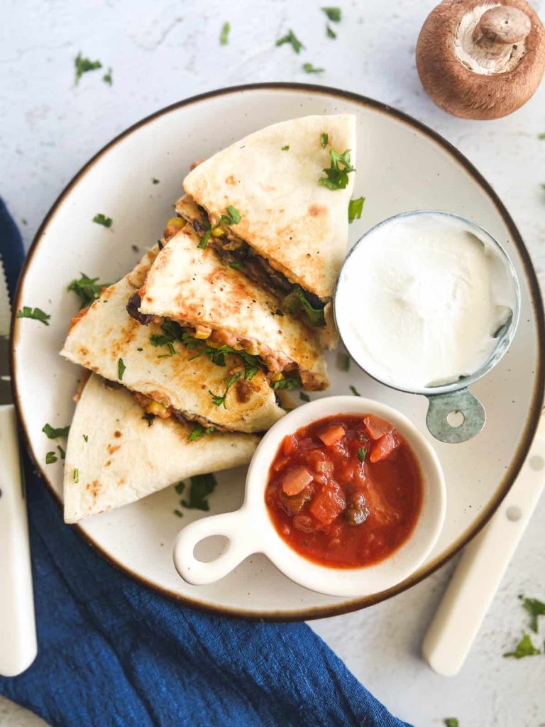 quesadilla on plate with salsa and sour cream cups