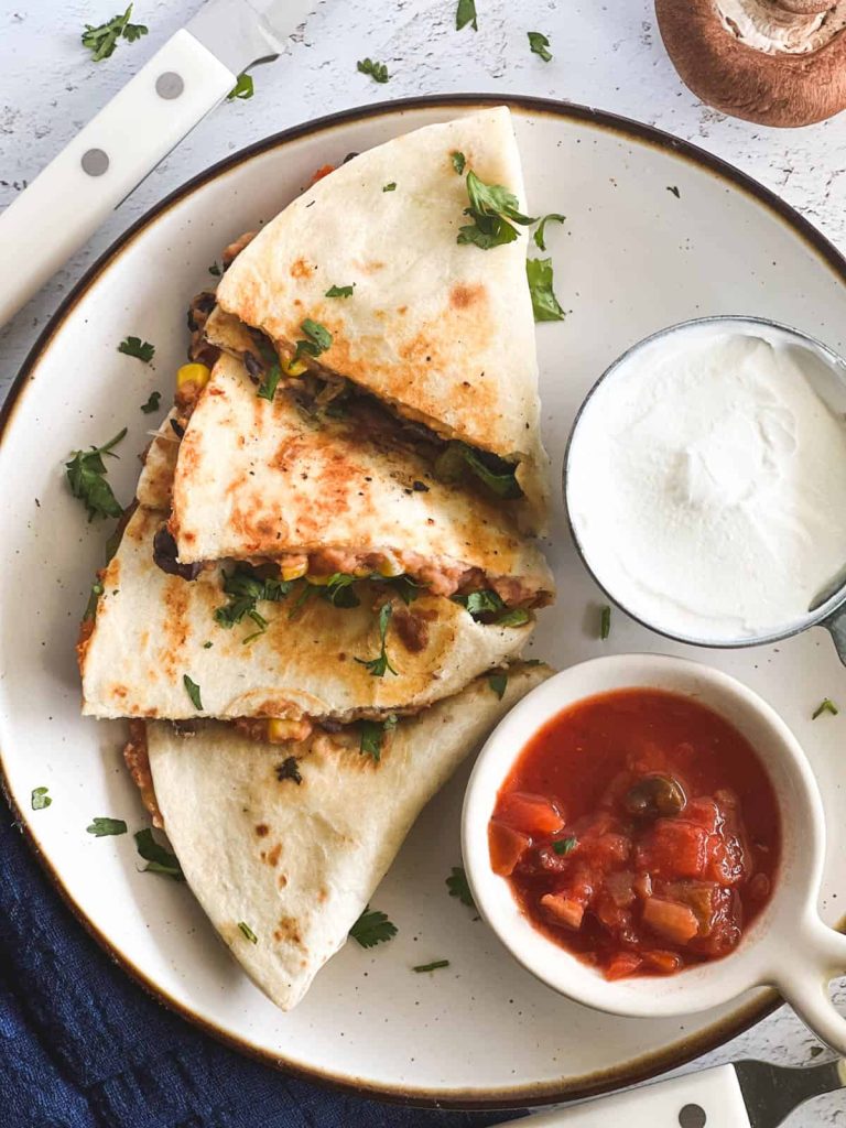 quesadilla on plate with salsa and sour cream cups