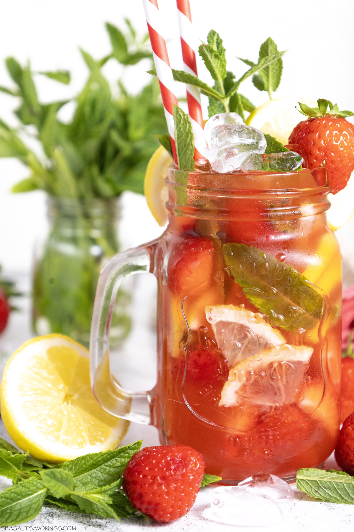 strawberry mojito mocktail with lots of fresh chopped fruit in a glass jar, overflowing with strawberry and mint garnish