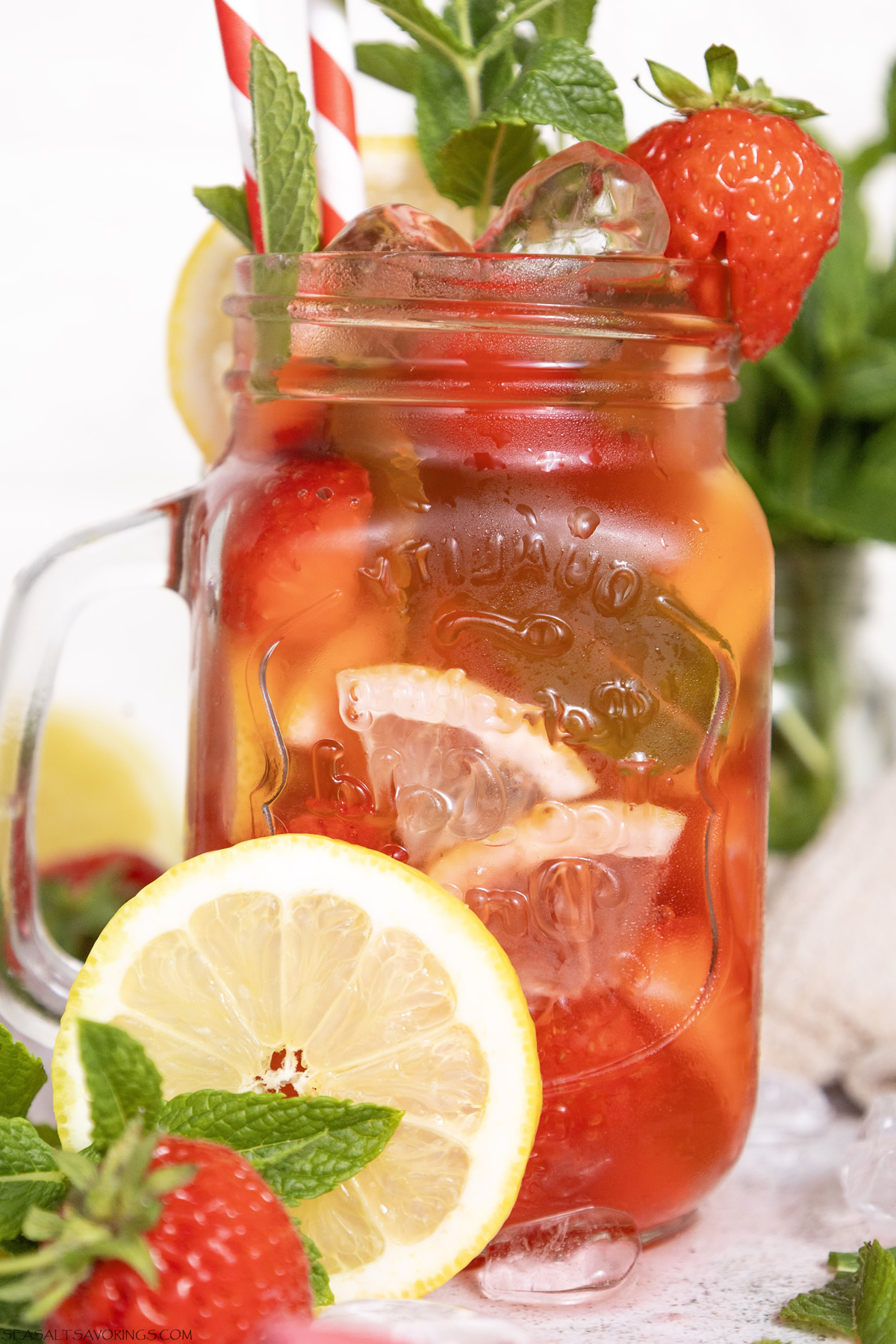strawberry mojito mocktail with lots of fresh chopped fruit in a glass jar, overflowing with strawberry and mint garnish