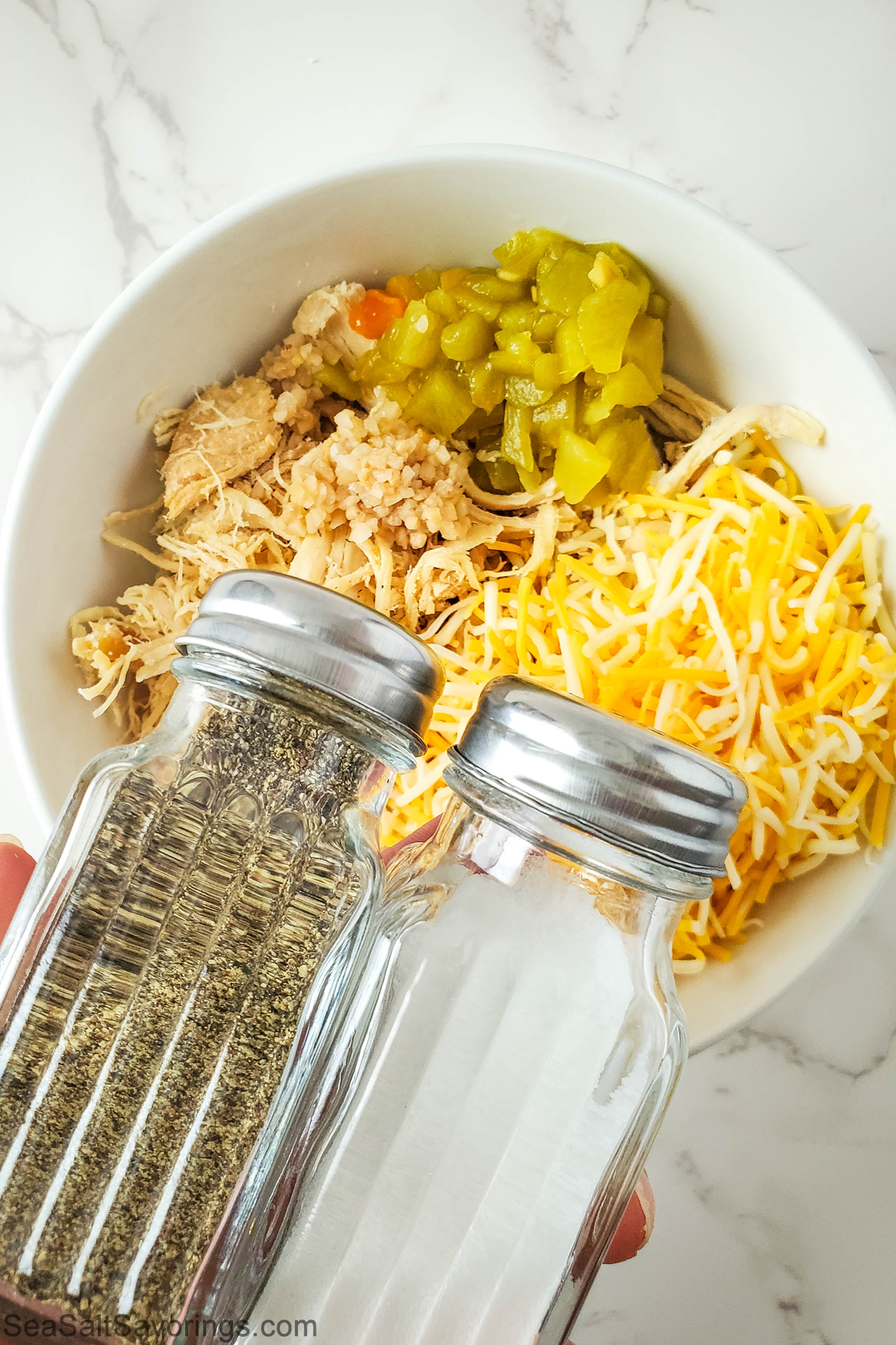 taquito filling in a bowl and a salt and pepper shaker about to be added to the bowl