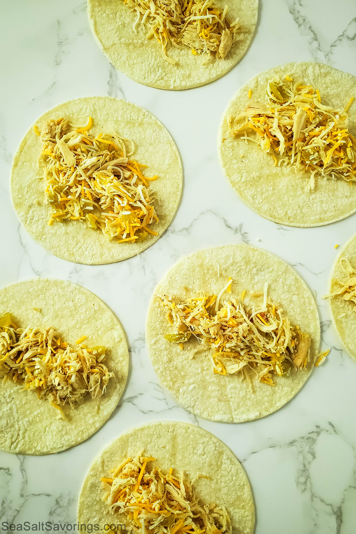 taquito tortillas laying flat with filling added on top