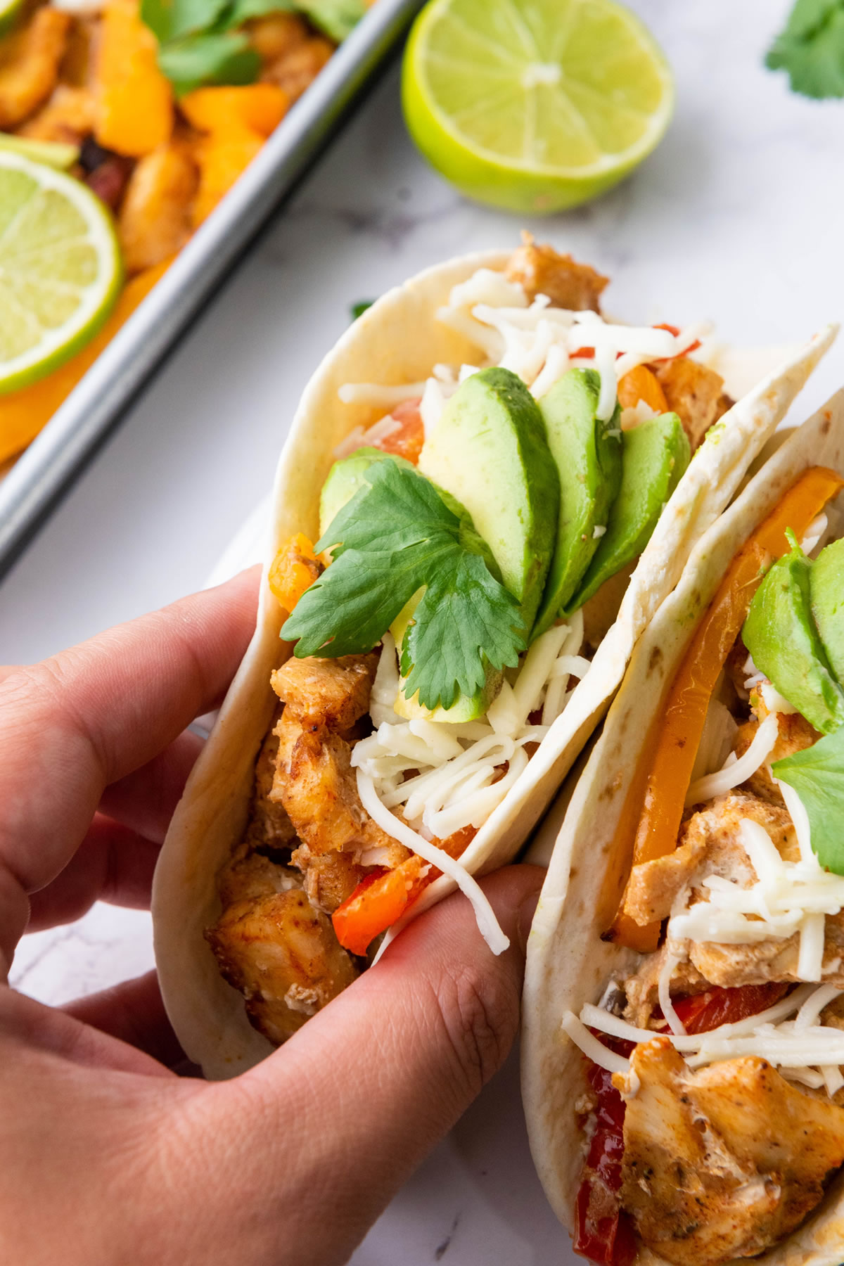 hand holding a chicken taco with fresh vegetable toppings