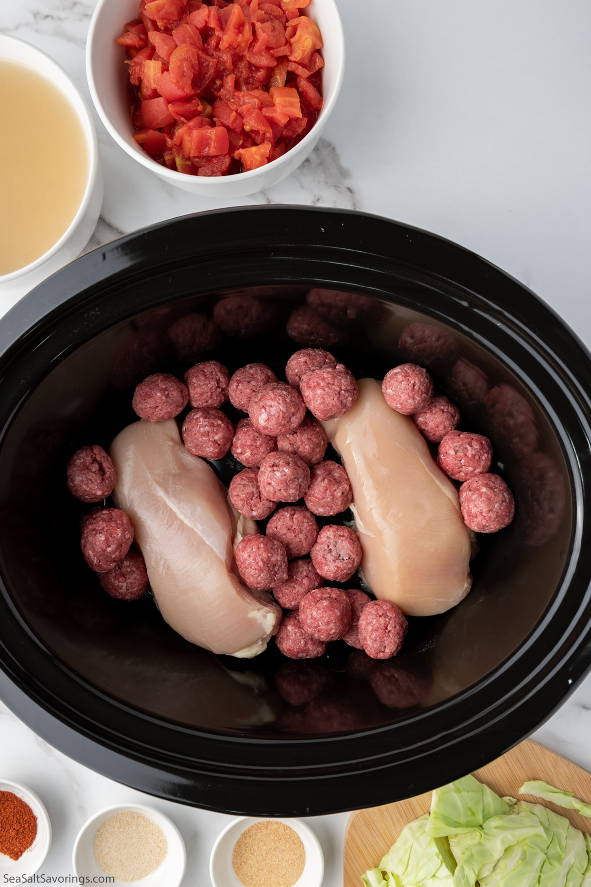 meatballs and chicken breast placed in crockpot