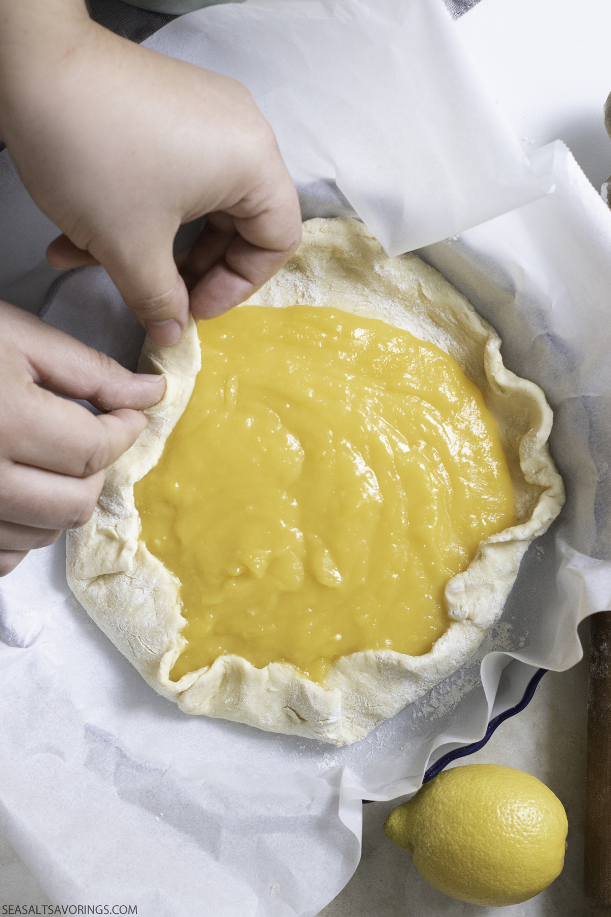 rolling the edges of dough over the lemon curd