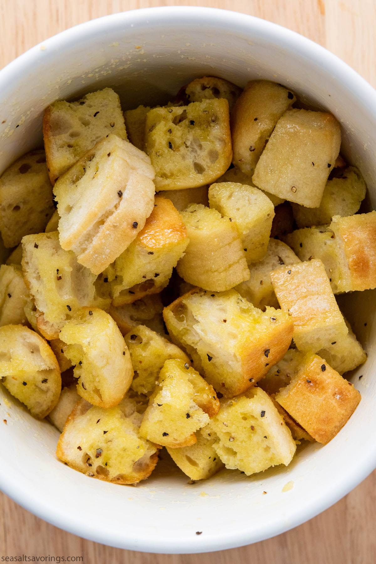 cubed ciabatta in a bowl sprinkled with oil and season