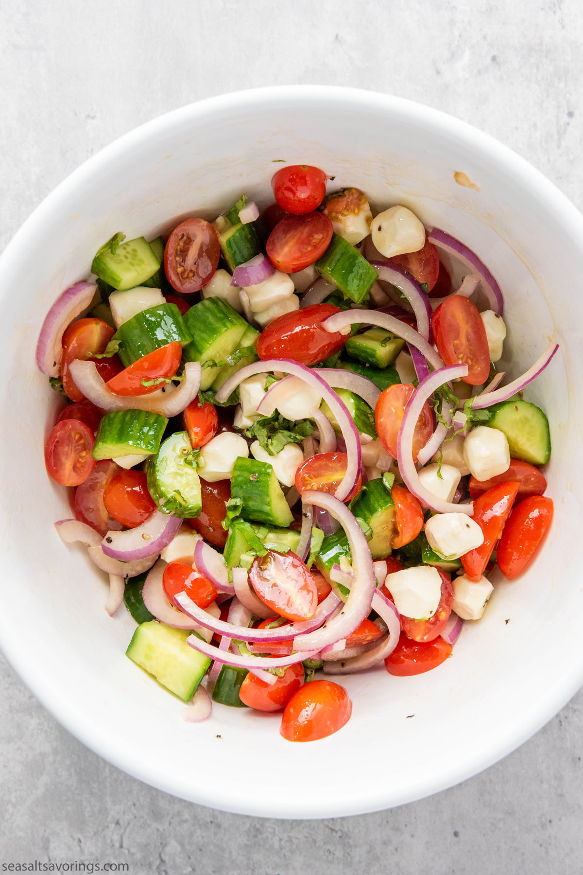 vegetable and cheese balls mixed in a bowl with dressing