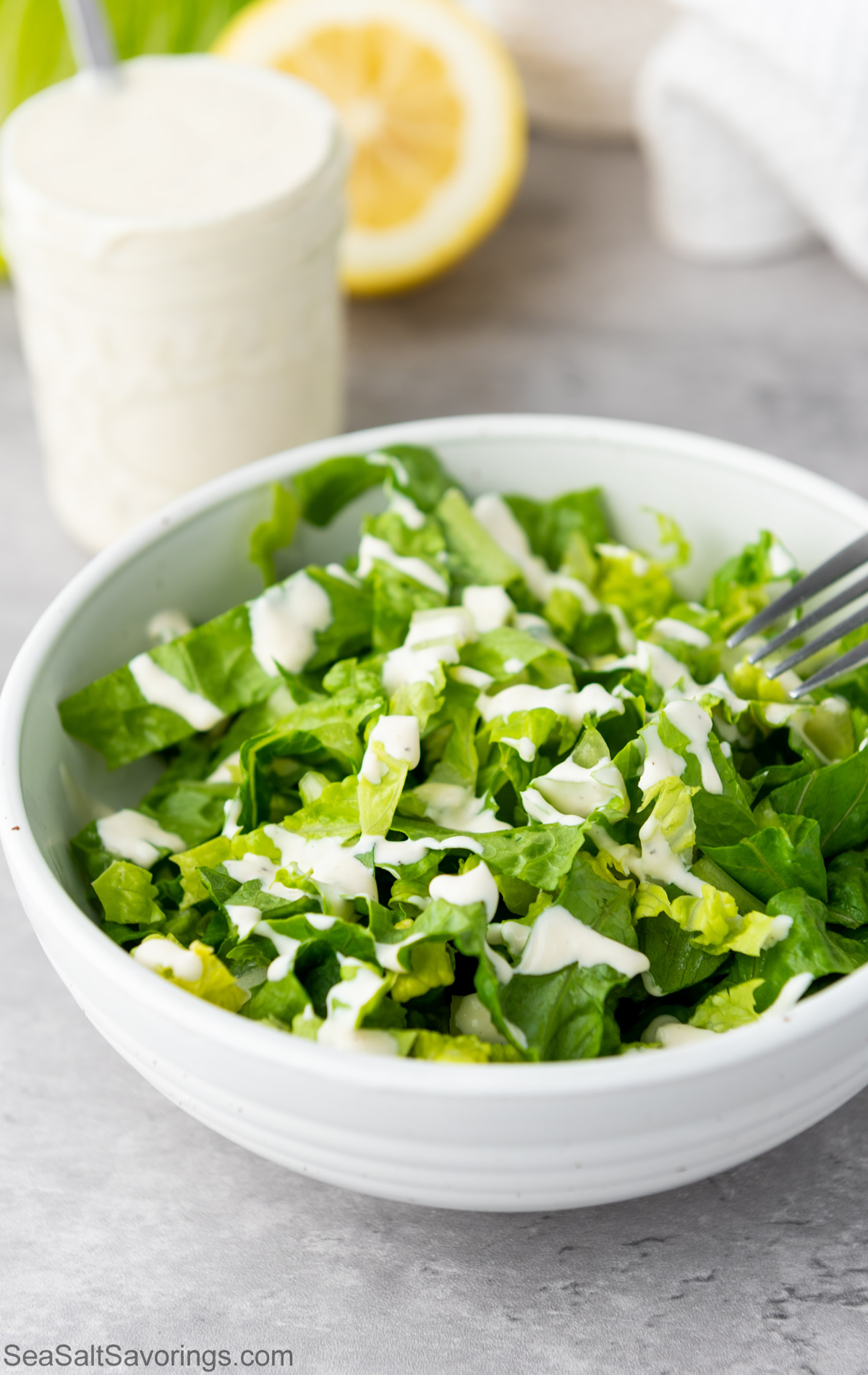 caesar salad next to jar of dressing