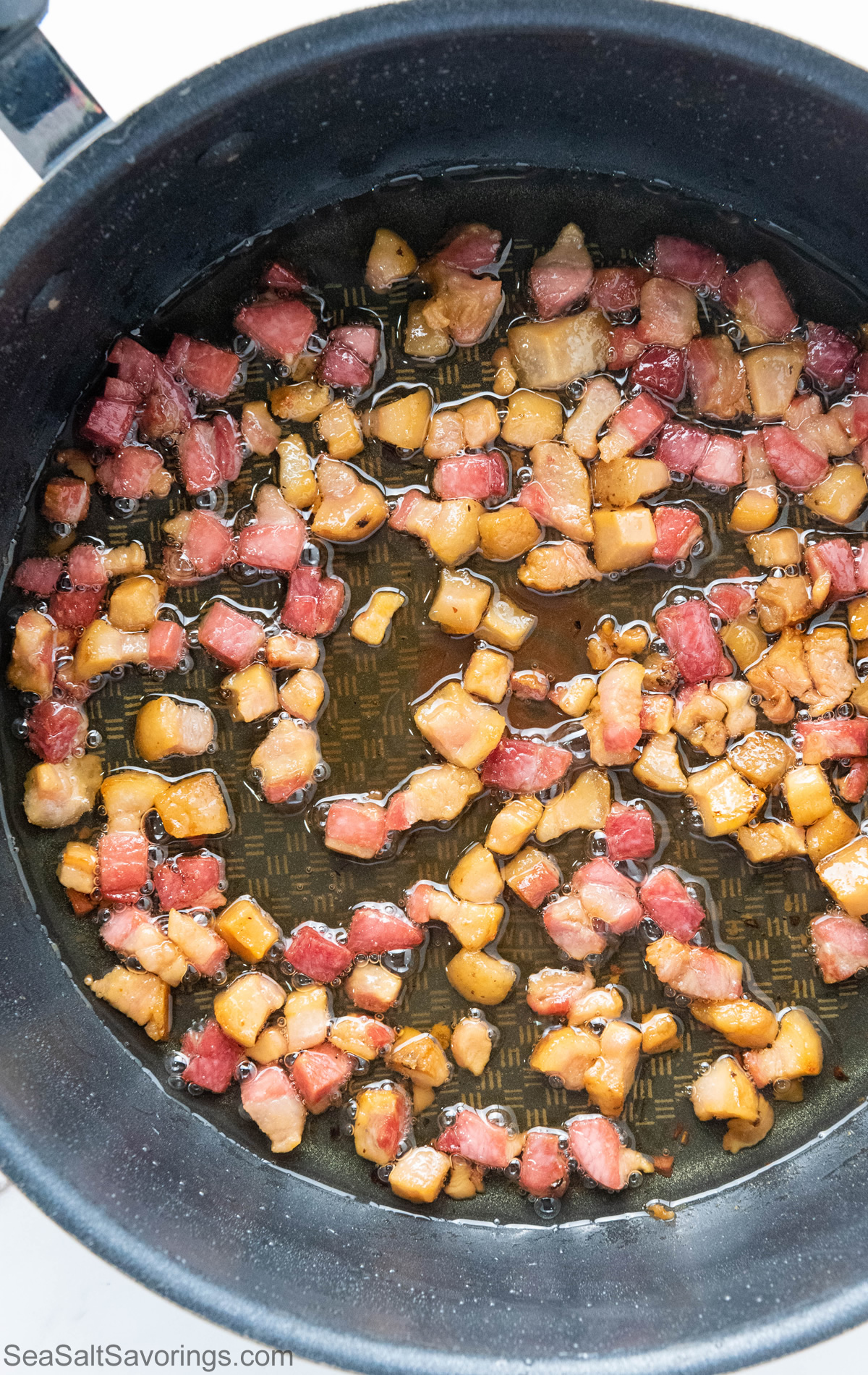 cubed pancetta cooking in a frying pan