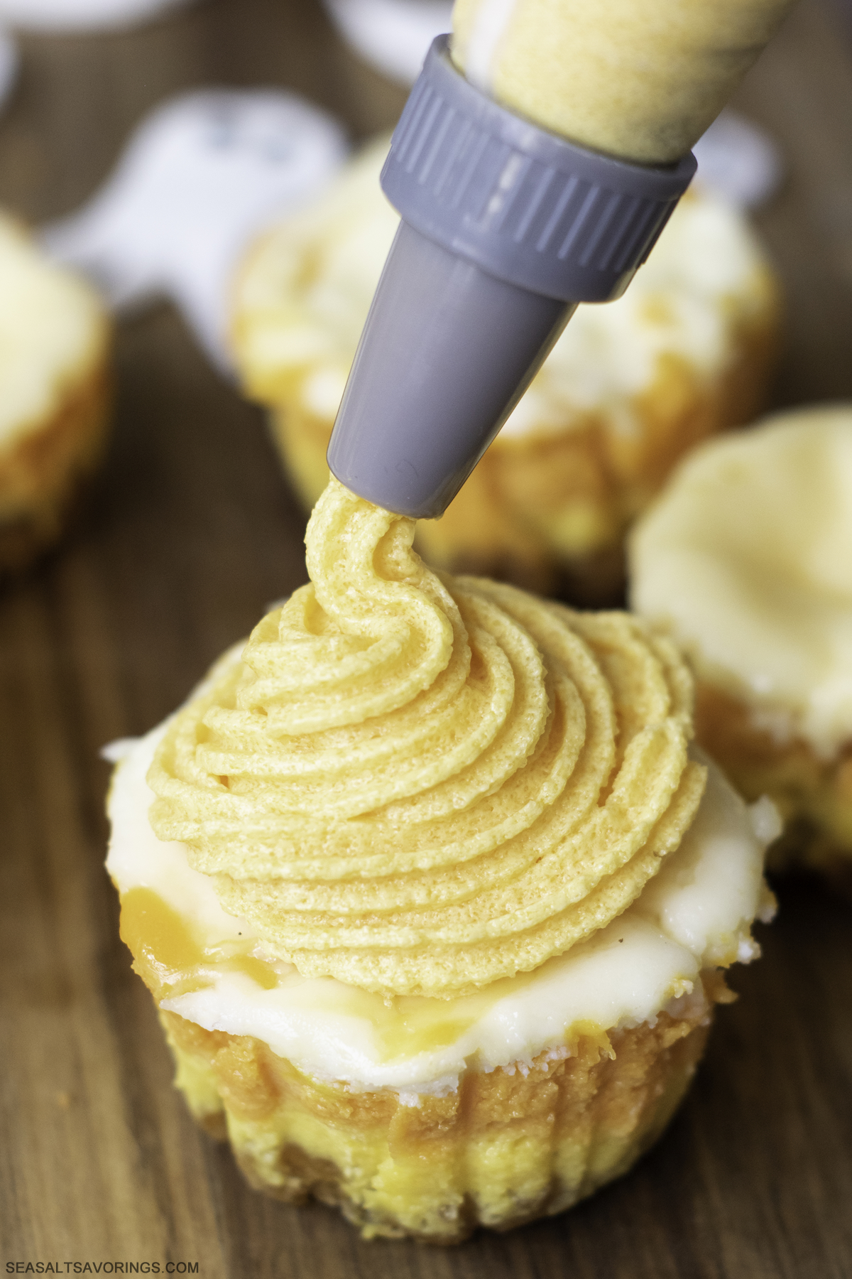 frosting tip squirting orange frosting onto a cheesecake