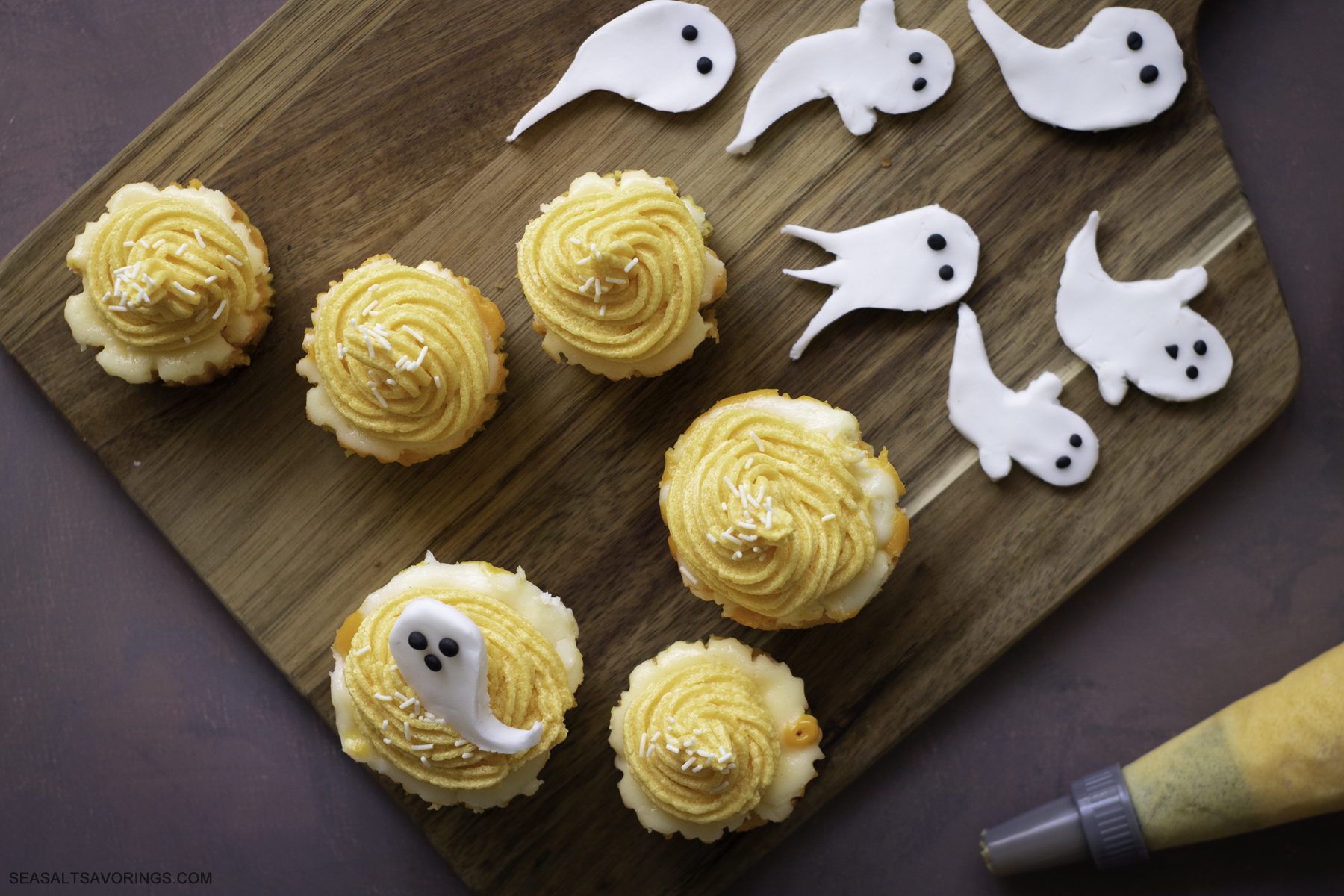 finished mini cheesecakes frosted on a cutting board next to ghost fondants