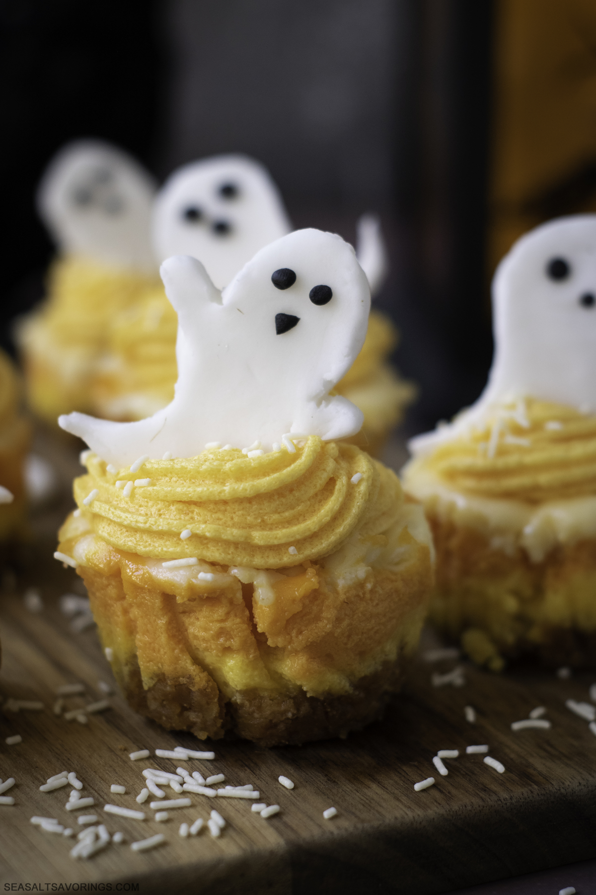 a candy ghost waving as it sits atop a mini cheesecake