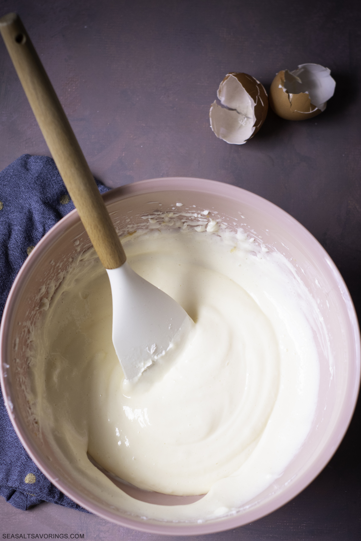 a mixing bowl full of batter being mixed by a wooden spoon