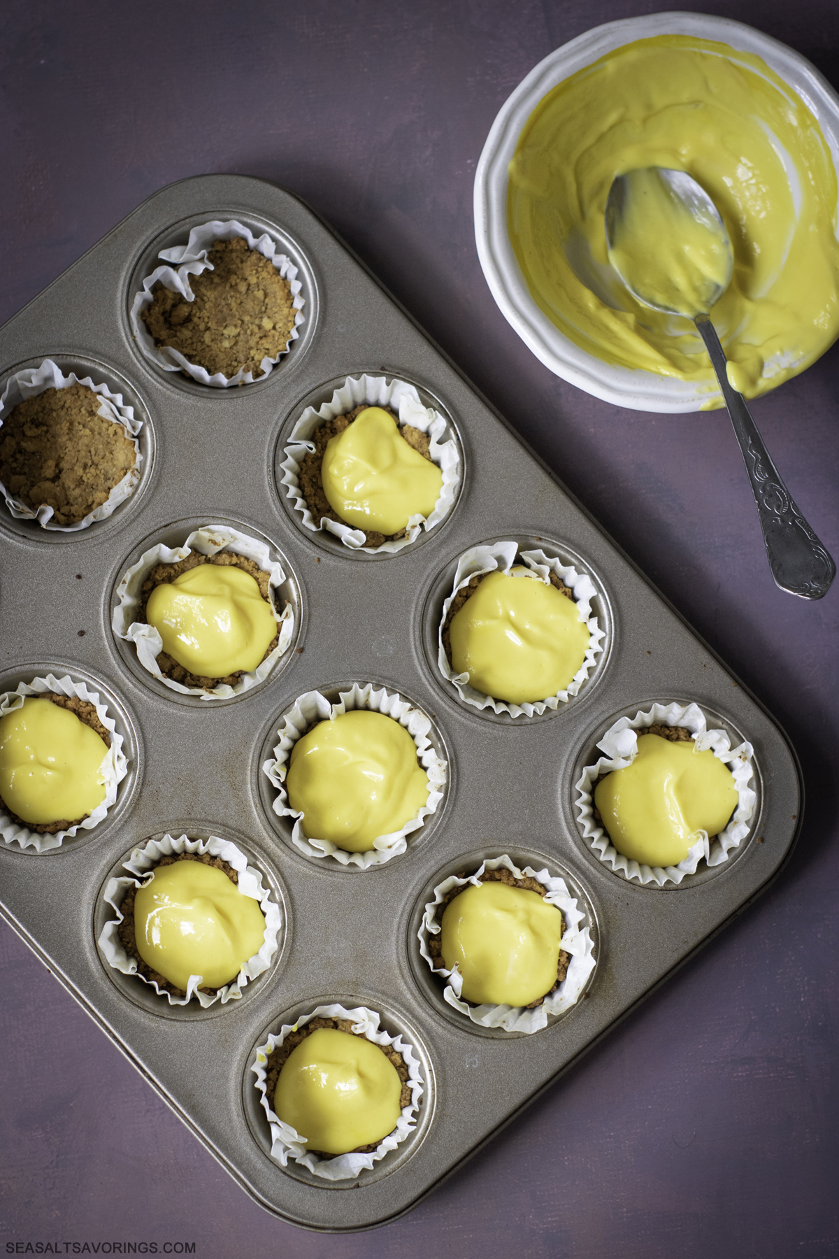 scooping batter into the graham cracker crumble lined baking liners