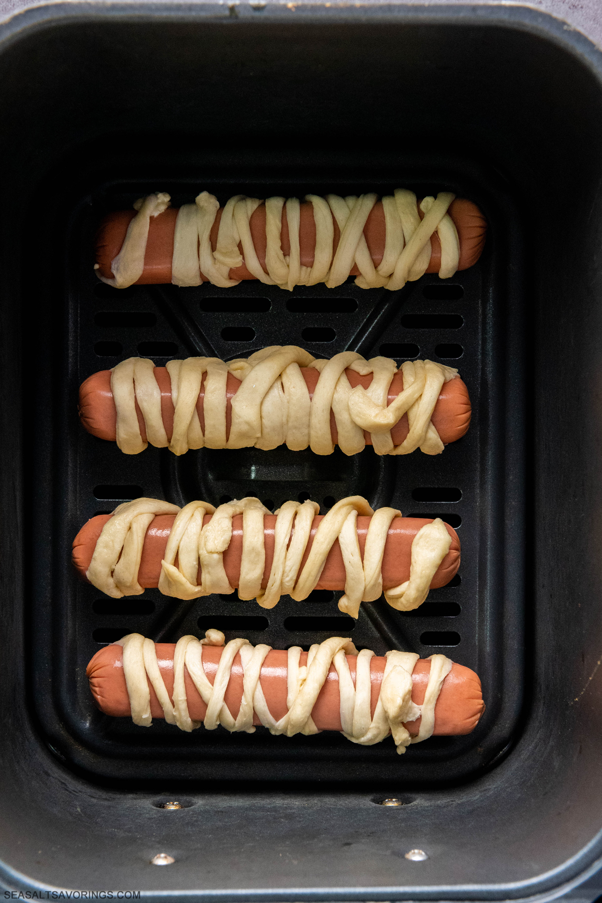 the dough wrapped hot dogs placed in an air fryer basket