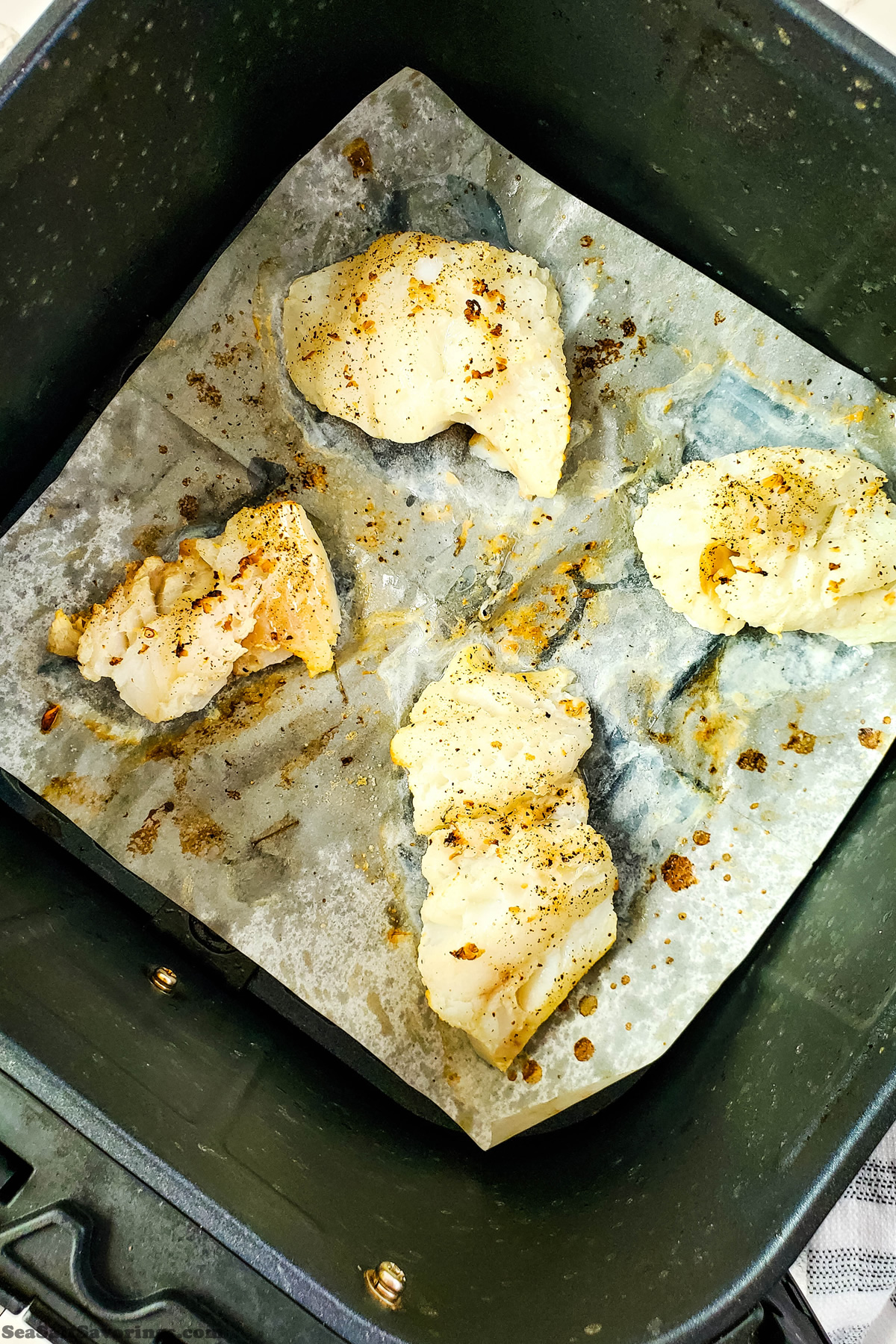 four well seasoned cod filets in a air fryer basket