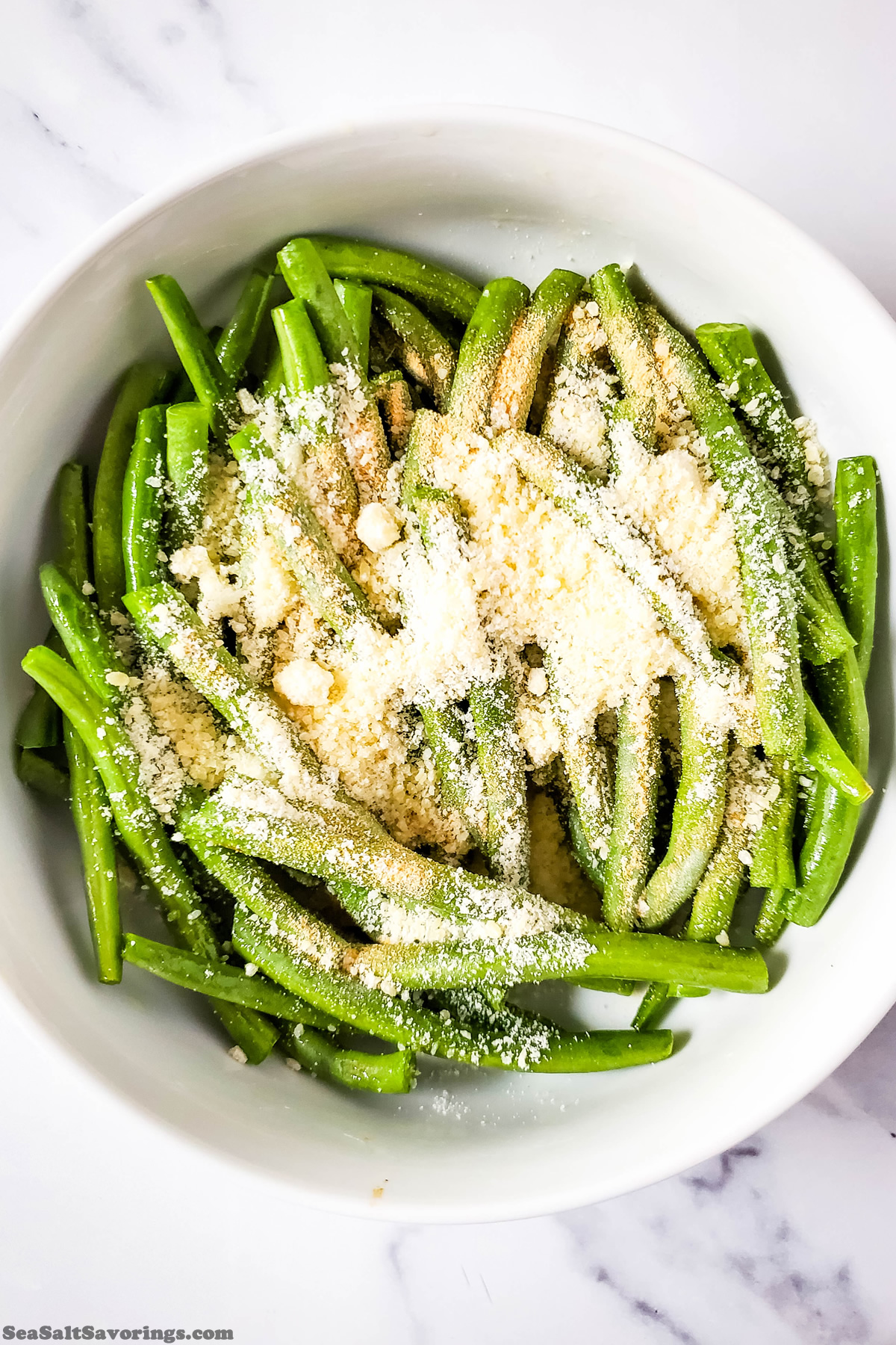 bowl of green beans about to be tossed with oil and garlic and parmesan