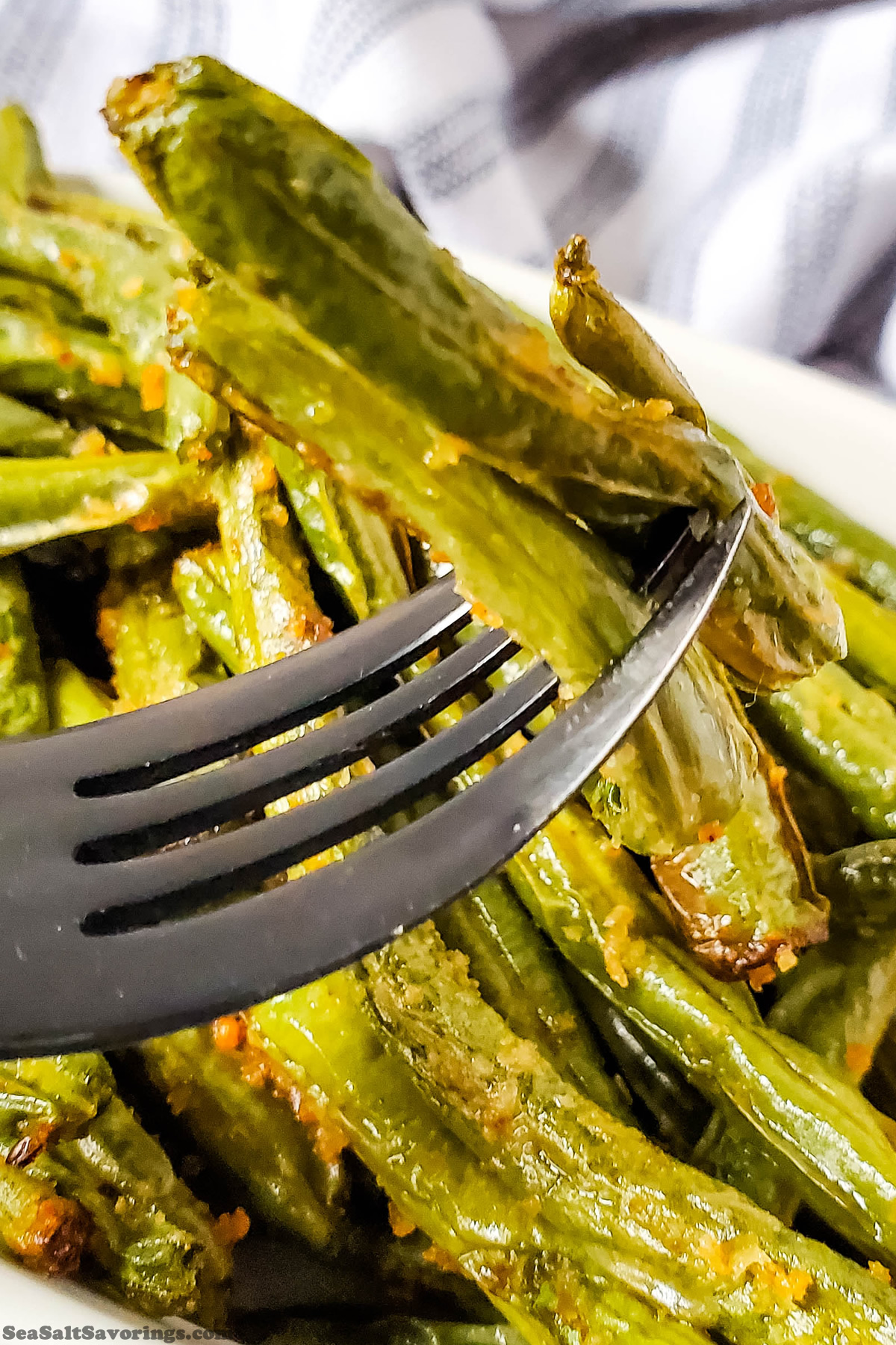 close up view of garlic parmesan green beans on a fork