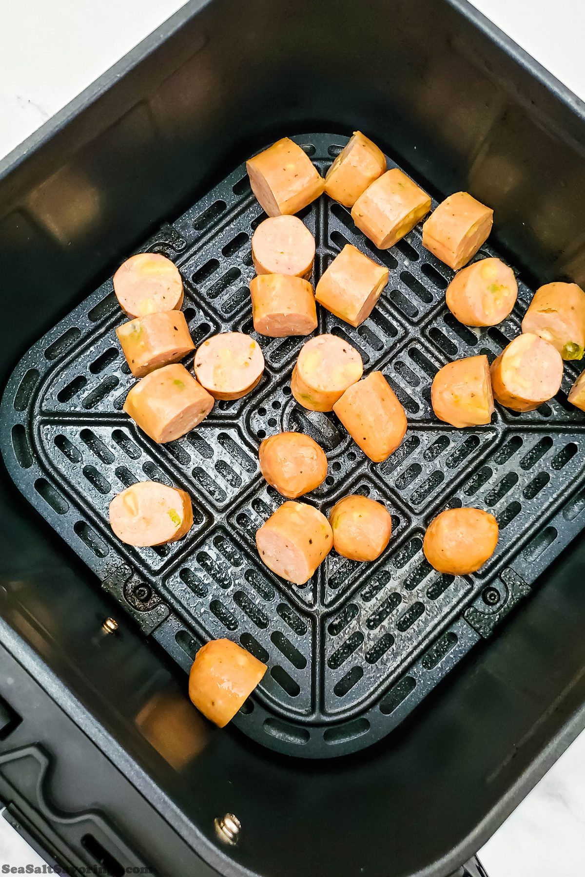 sausage pieces sliced into bite sized pieces placed in a air fryer basket