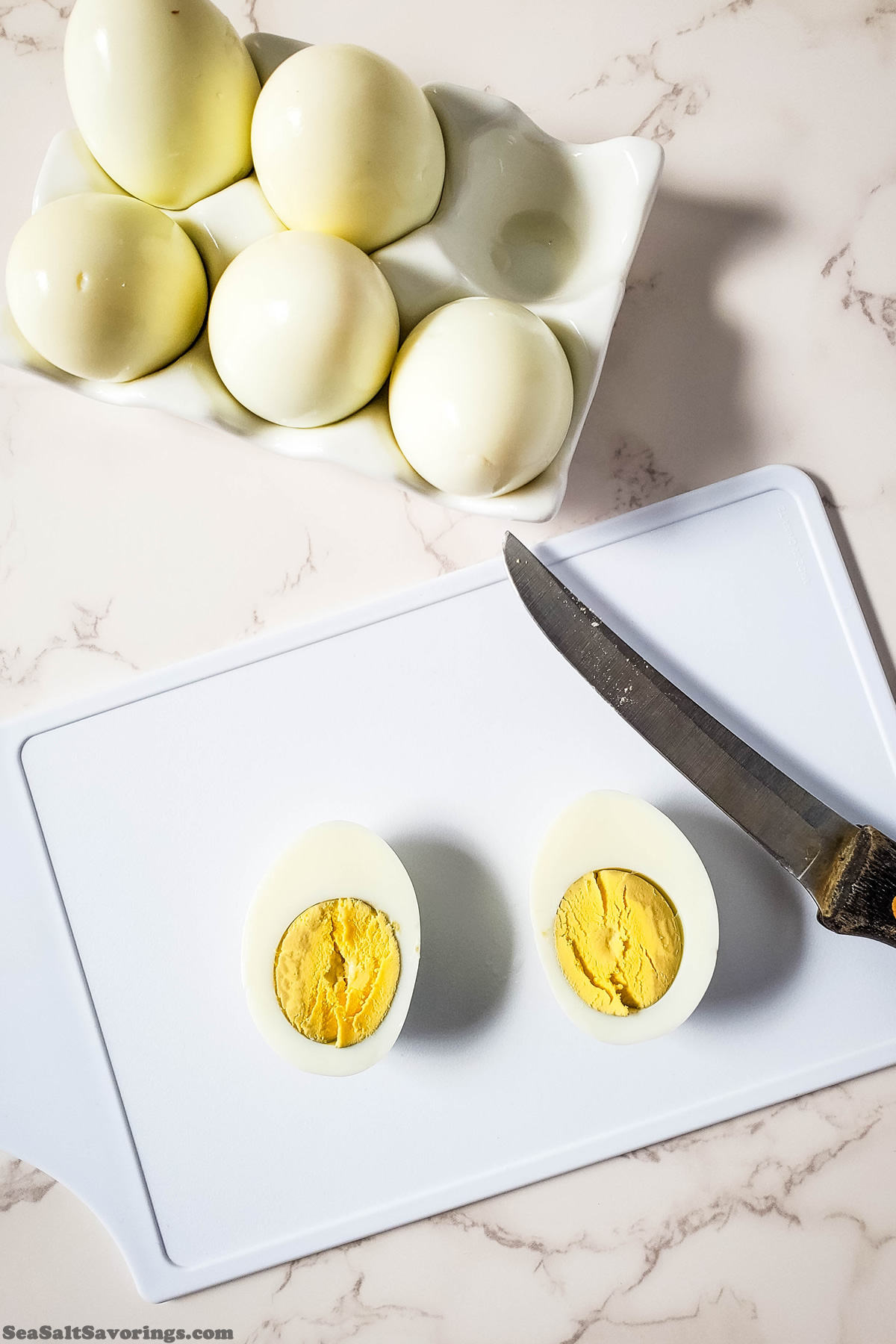 cutting board with knife showing an egg sliced in half