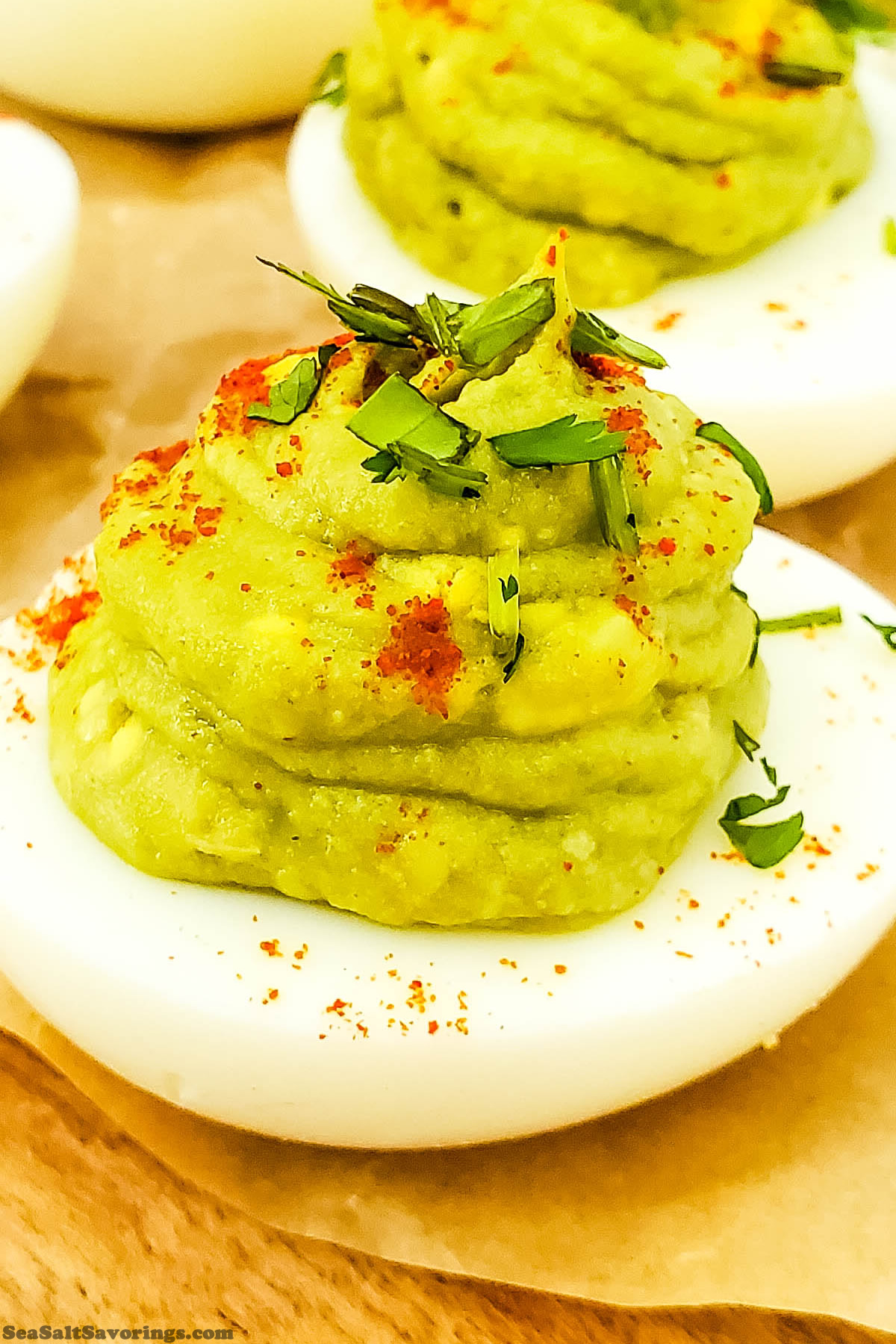 close up view of an avocado deviled egg with garnish, the filling is green