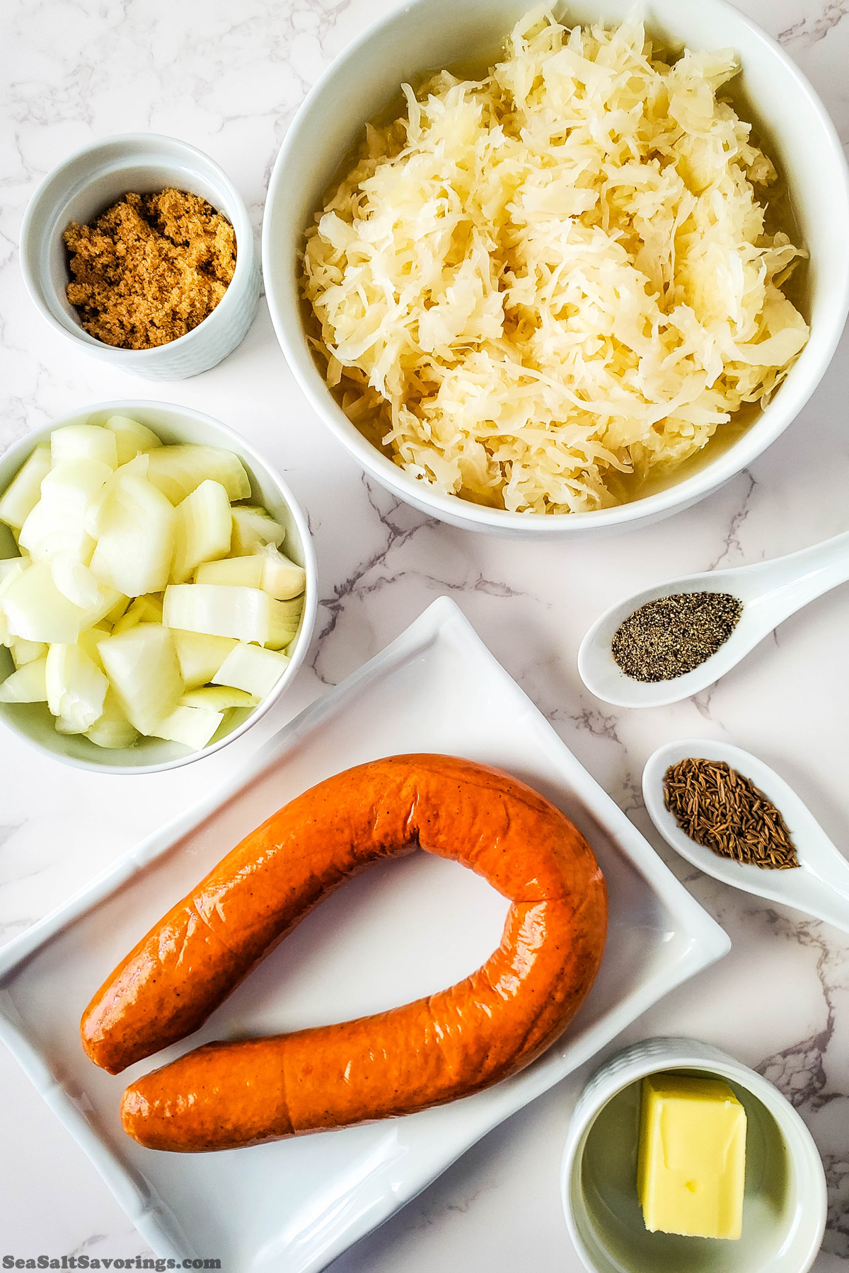 simple ingredients for kielbasa sourkraut including a bowl of sourkraut and brown sugar and onion