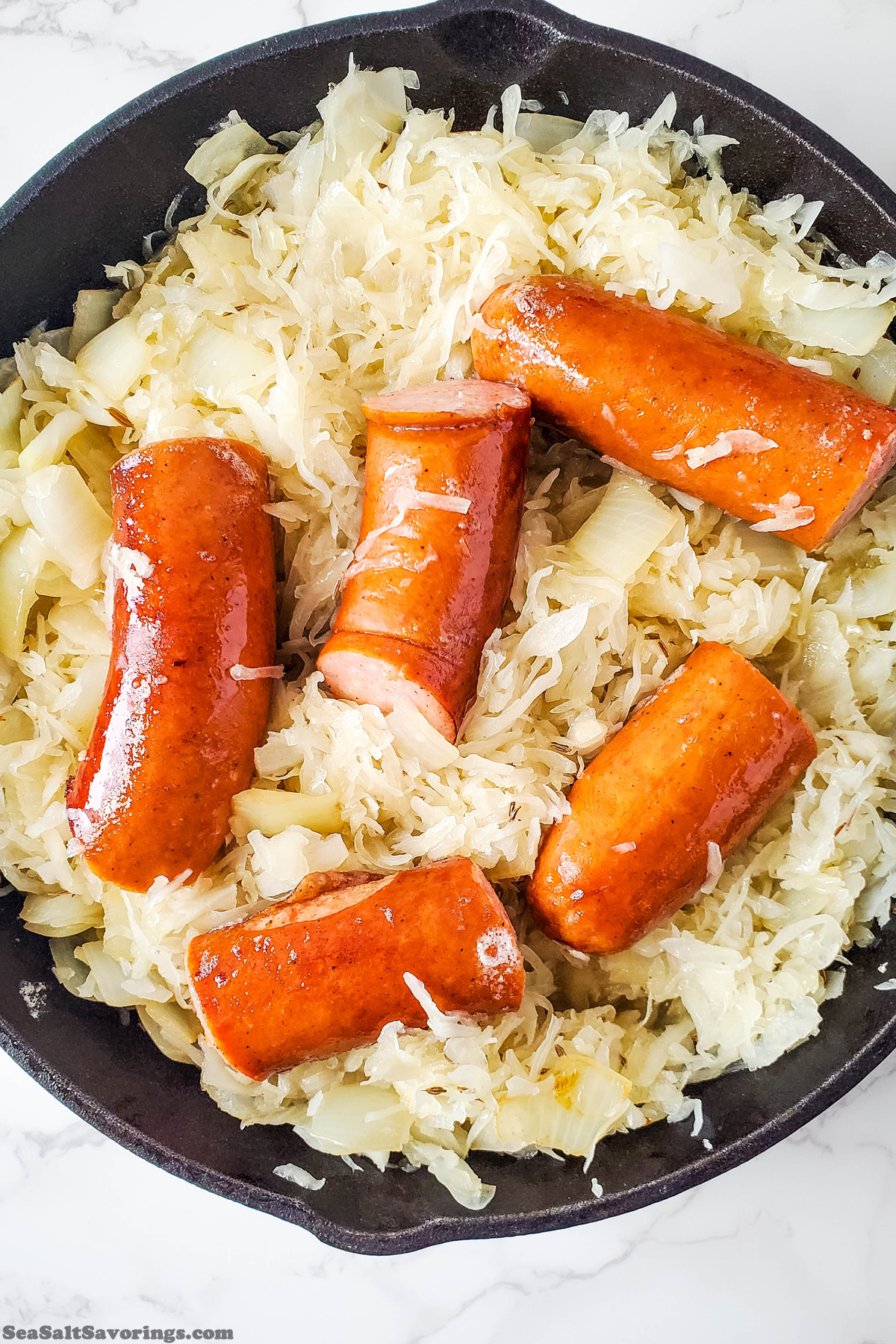 mixing kielbasa and sourkraut mixture together in the same pan